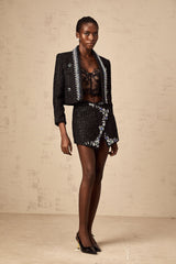 A black crystal tweed jacket and matching skirt set named Delphine featuring a textured fabric with sparkly accents