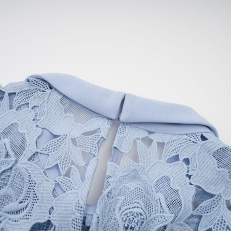 A blue midi dress with floral lace appliques and a delicate floral pattern throughout the fabric