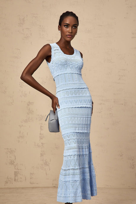 A blue midi dress with ruffled trim and crochet knit texture worn by a model standing against a plain background