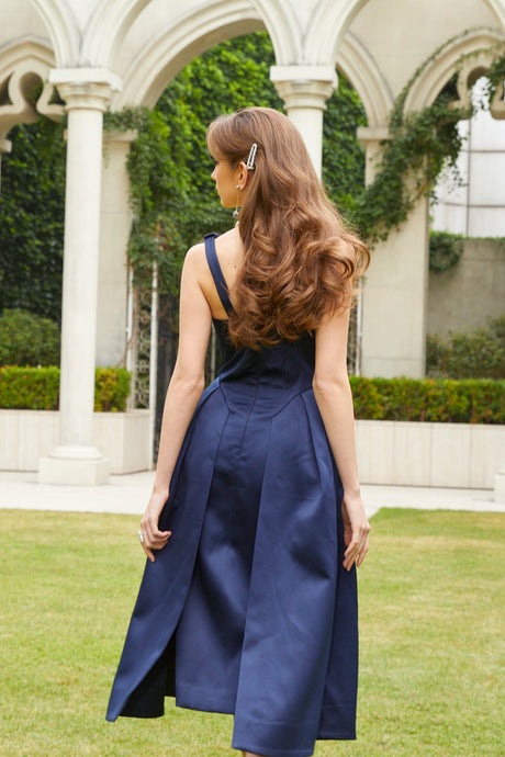 A blue satin midi dress with a twist detail at the waist featuring a sleek silhouette and shiny fabric
