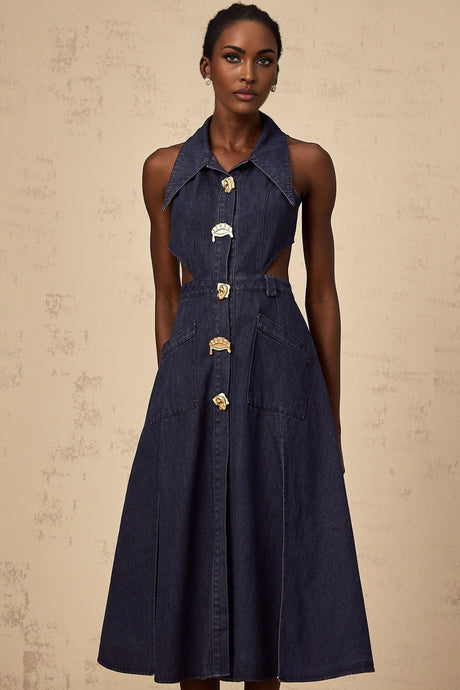 A dark blue denim midi dress with cut out details on a plain background