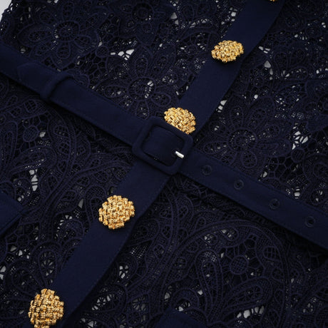 A dark blue midi dress with a floral crochet lace pattern worn by a model standing against a plain background