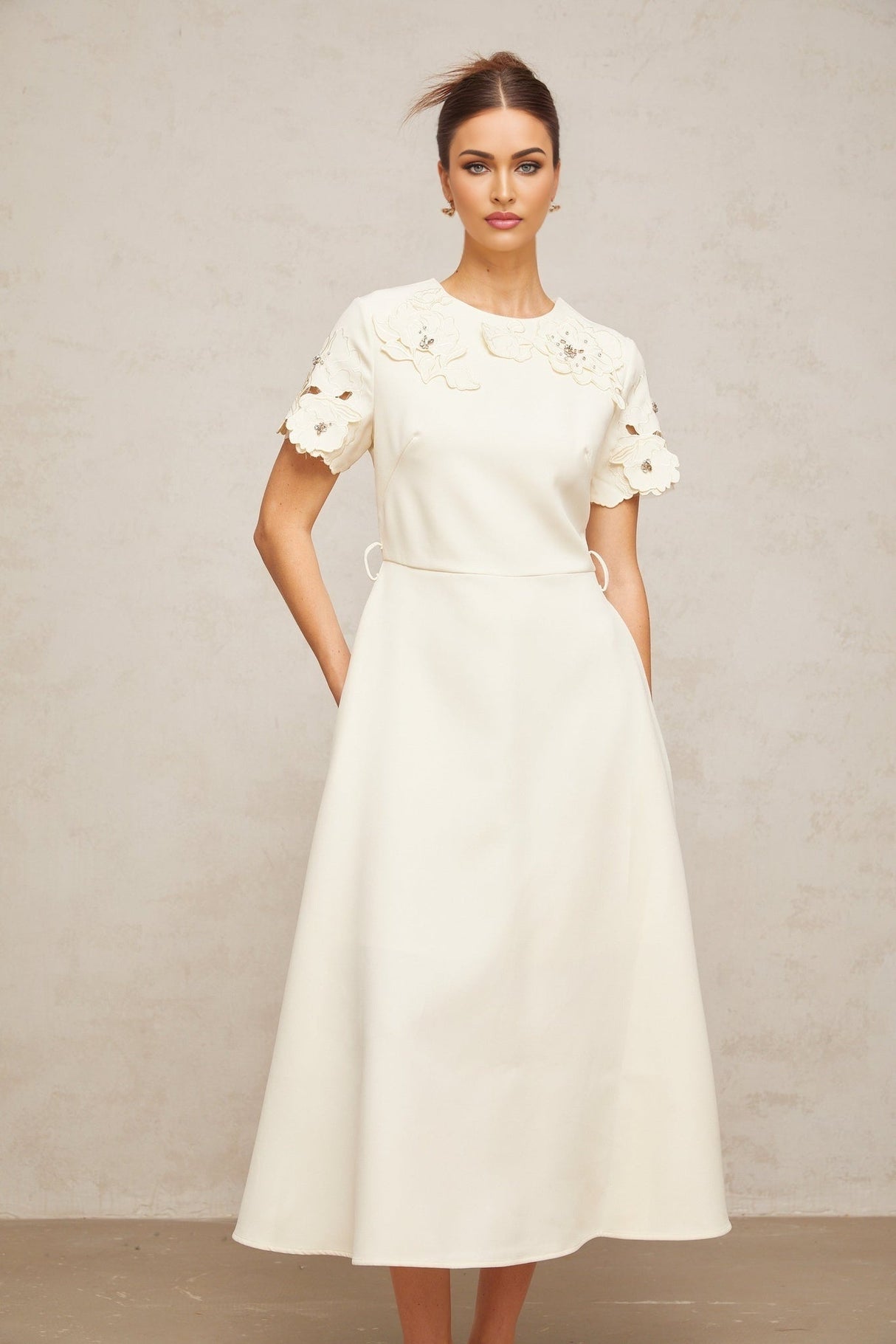 A flared midi dress in neutral tones featuring orange floral appliques on the fabric