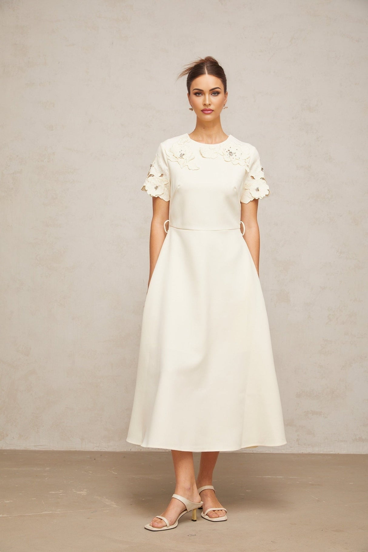 A flared midi dress in neutral tones featuring orange floral appliqués on the fabric