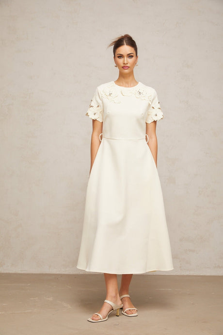A flared midi dress in neutral tones featuring orange floral appliqués on the fabric