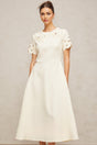 A flared midi dress in neutral tones featuring orange floral appliqués on the fabric