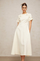 A flared midi dress in neutral tones featuring orange floral appliqués