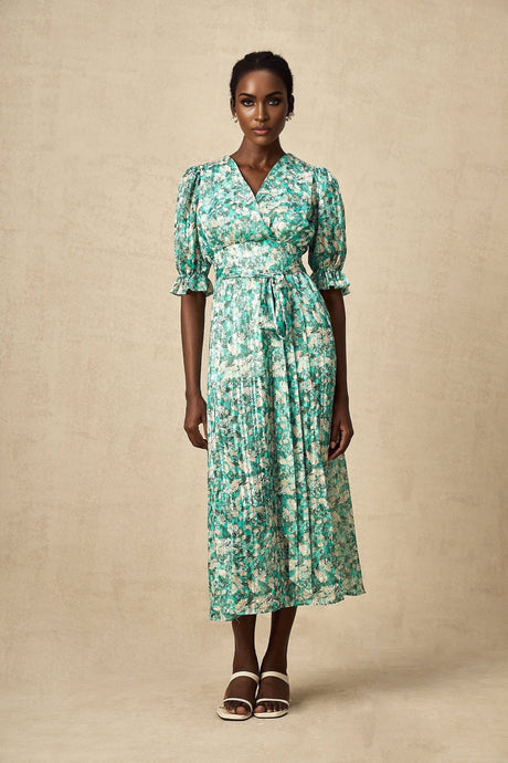 A green midi dress with a floral print pattern and a high slit featuring a feminine silhouette and flowing design