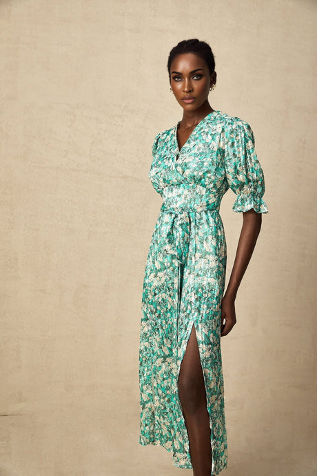 A green midi dress with a floral print pattern and a high slit featuring a feminine silhouette and flowing fabric