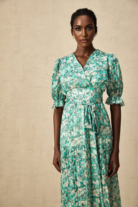 A green midi dress with a floral print pattern and a high slit featuring a sleeveless design and a fitted silhouette