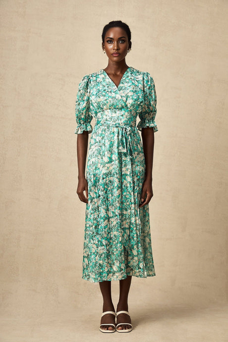 A green midi dress with floral print and high slit worn by a model standing against a plain background