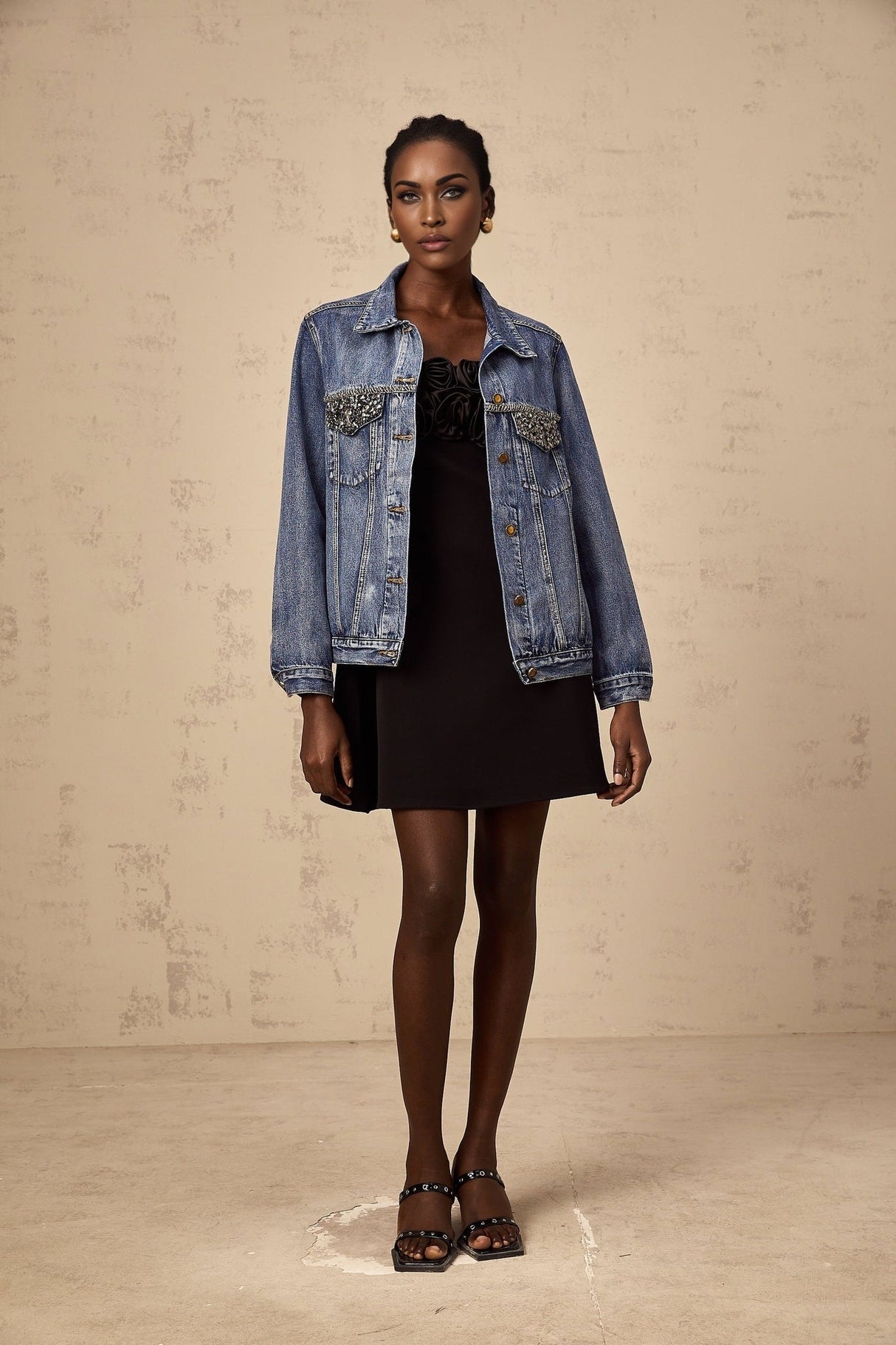 A light blue denim jacket adorned with sparkling rhinestones featuring a classic collar and button front closure