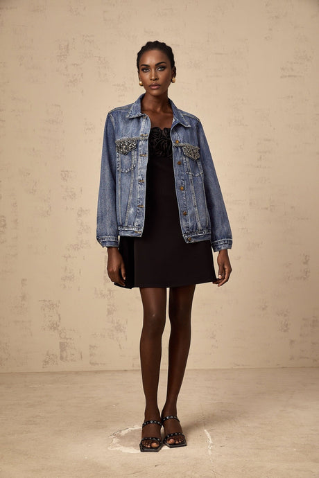 A light blue denim jacket adorned with sparkling rhinestones featuring a classic collar and button front closure