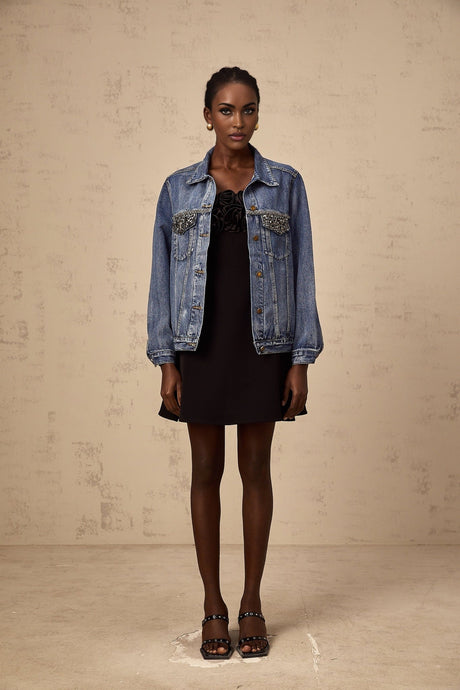 A light blue denim jacket adorned with sparkling rhinestones featuring a classic collar and button front closure