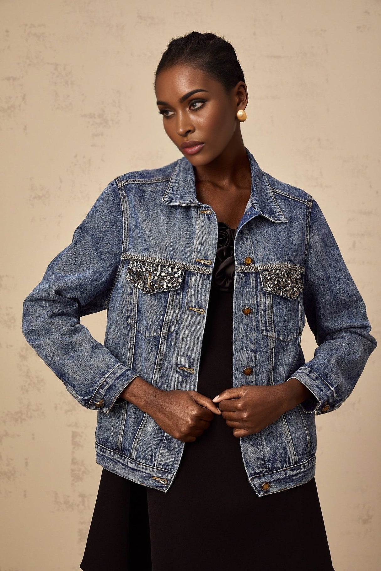 A light blue denim jacket adorned with sparkling rhinestones featuring a feminine and glamorous design