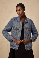 A light blue denim jacket adorned with sparkling rhinestones featuring a feminine and glamorous design