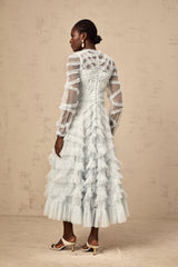 A light blue midi dress with small white polka dots featuring ruffled details and a feminine silhouette