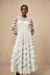 A light blue midi dress with small white polka dots featuring ruffled details and a flowy silhouette