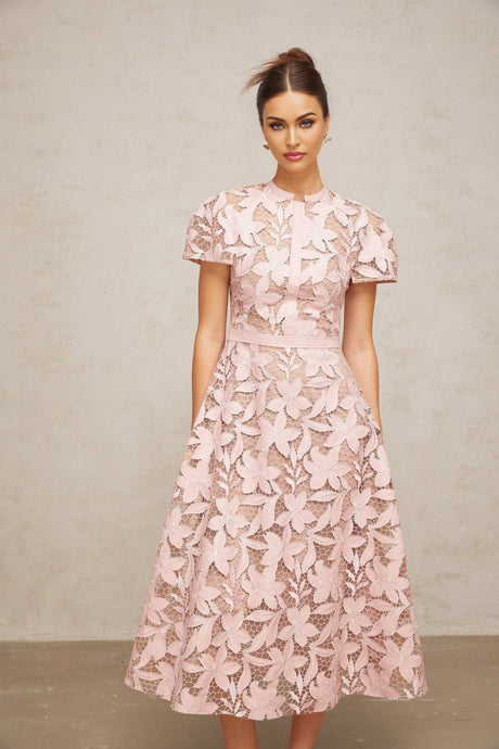 A pink midi dress made of guipure lace with intricate floral patterns and a delicate feminine design