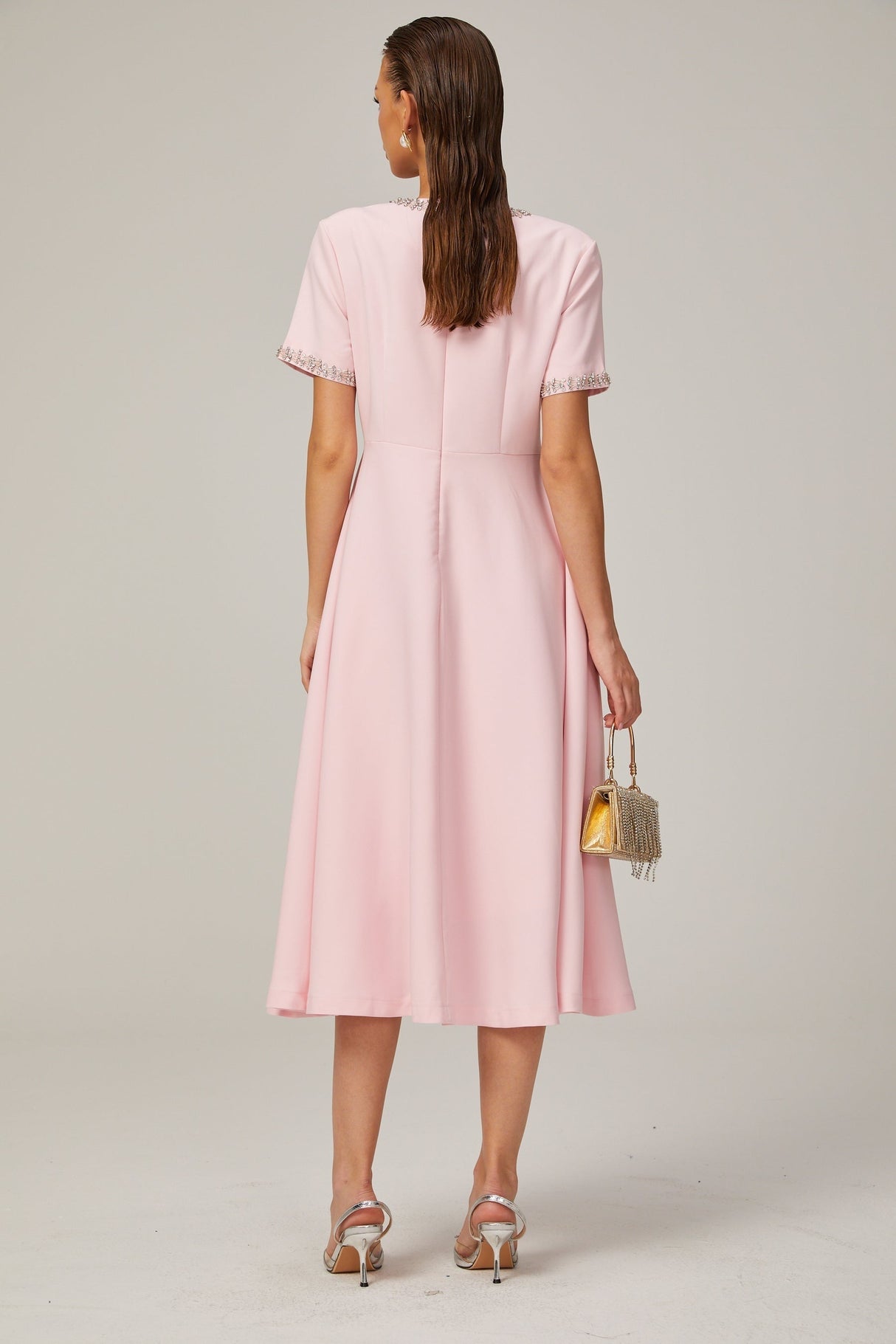 A pink midi dress with a crystalaccented bow and a Cassiopeiainspired design