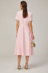 A pink midi dress with a crystalaccented bow and a Cassiopeiainspired design