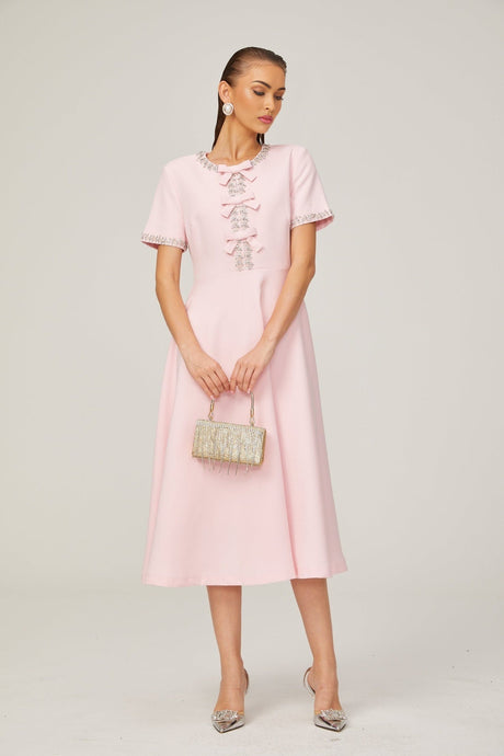 A pink midi dress with a crystalaccented bow detail and a Cassiopeia inspired design