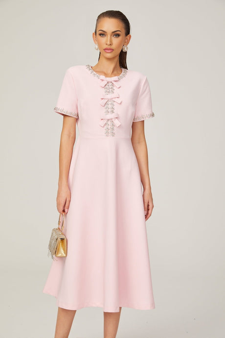 A pink midi dress with a crystalaccented bow detail and a Cassiopeia inspired design
