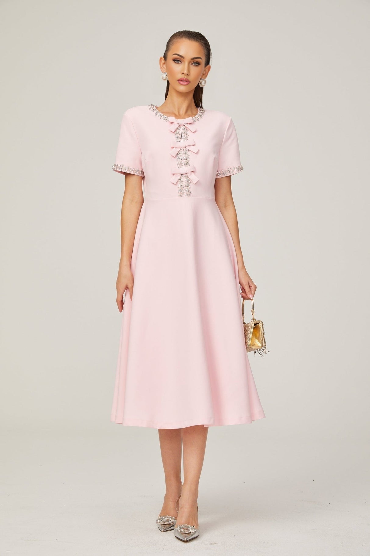 A pink midi dress with a crystalaccented bow detail and a feminine silhouette named Cassiopeia