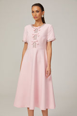 A pink midi dress with a crystalaccented bow detail and a fitted silhouette named Cassiopeia