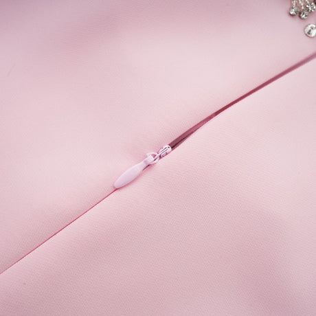 A pink midi dress with a crystalaccented bow detail featuring a Cassiopeia inspired design