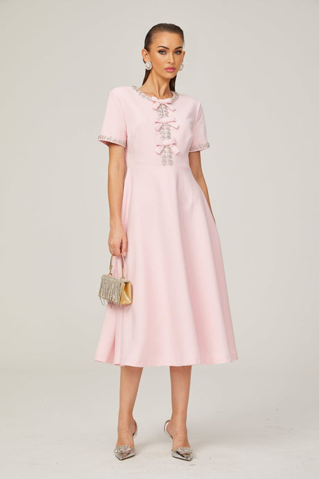 A pink midi dress with a crystalaccented bow detail inspired by the Cassiopeia constellation featuring a feminine silhouette and elegant design