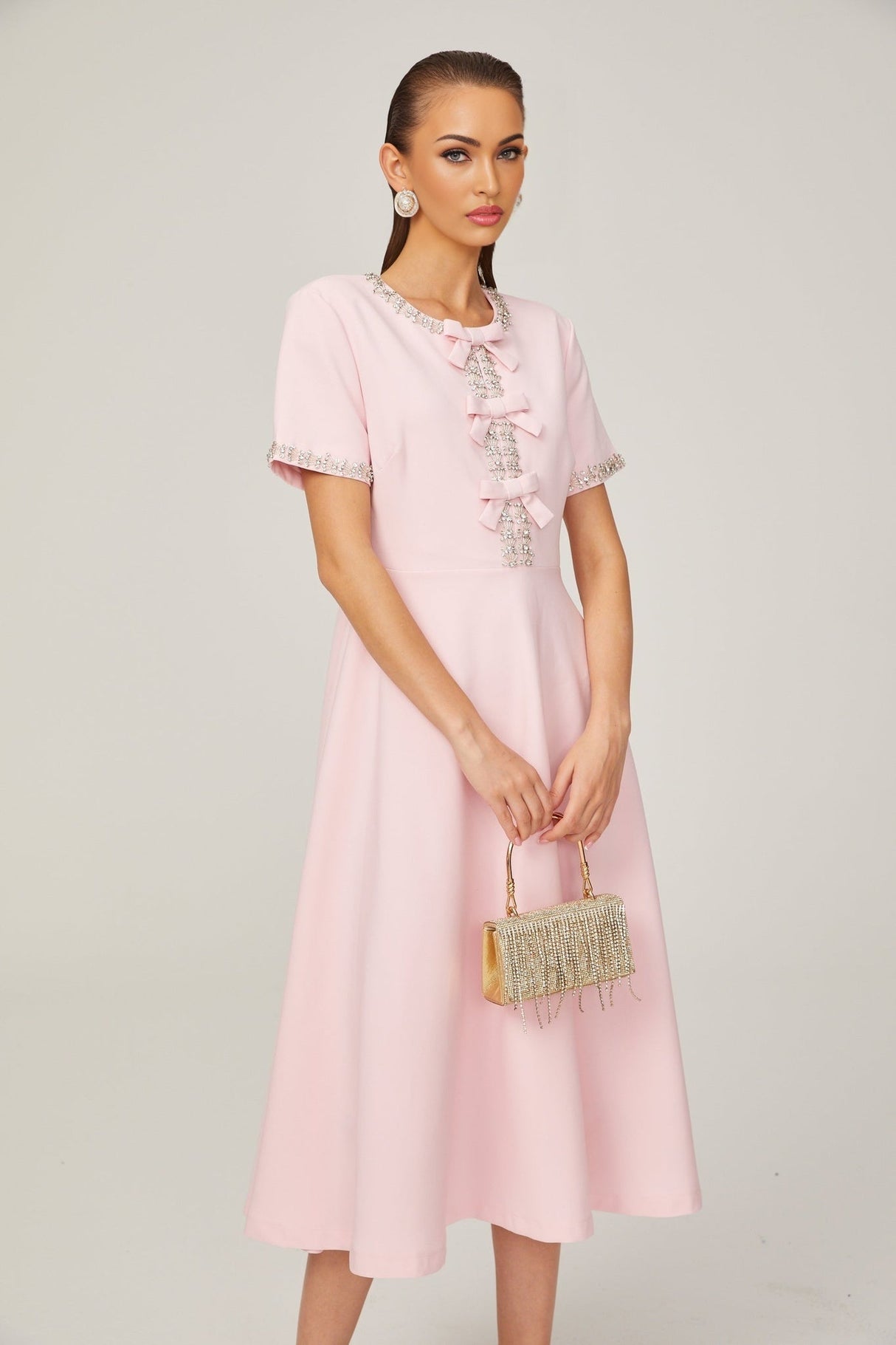 A pink midi dress with a crystalaccented bow detail inspired by the constellation Cassiopeia