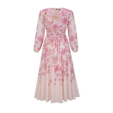 A pink midi dress with a floral print pattern worn by a model standing against a plain background