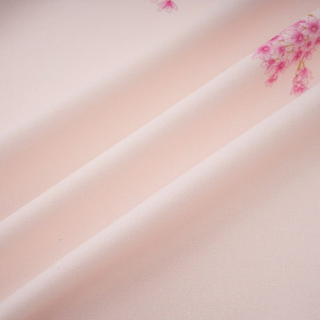 A pink midi dress with a floral print pattern worn by a model standing against a plain background
