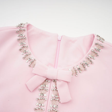 A pink midi dress with a large bow accent adorned with crystal embellishments inspired by the Cassiopeia constellation
