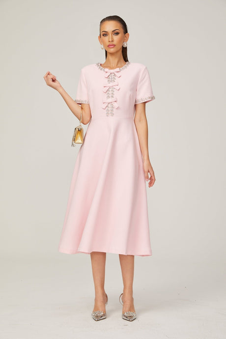 A pink midi dress with a large bow detail and crystal accents inspired by the Cassiopeia constellation