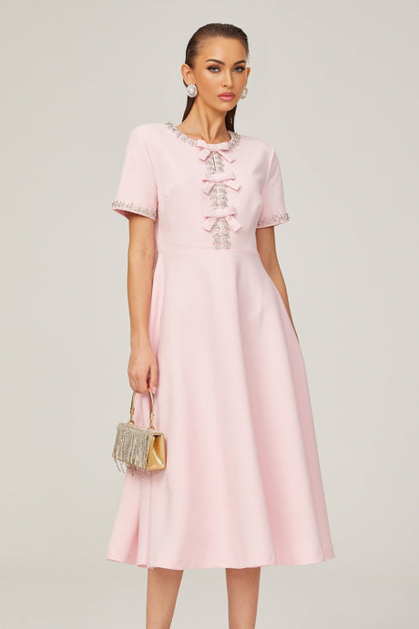 A pink midi dress with a large bow detail and crystal accents inspired by the Cassiopeia constellation