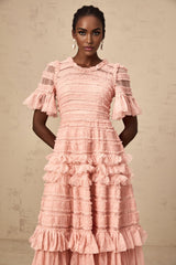 A pink midi dress with a ruffled tulle skirt and small dot details throughout featuring a fitted bodice and delicate shoulder straps