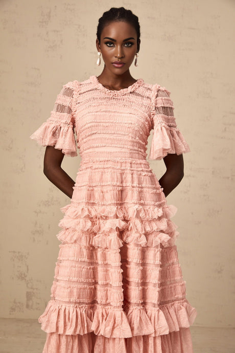 A pink midi dress with a ruffled tulle skirt and small dot details throughout featuring a fitted bodice and delicate shoulder straps