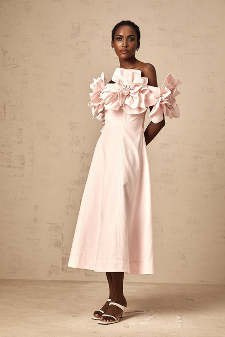 A pink midi dress with an offshoulder neckline featuring three dimensional petal details throughout the garment named Juliette