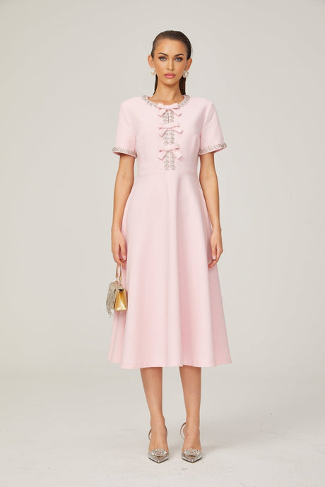 A pink midi dress with crystal accents and a prominent bow detail inspired by the Cassiopeia constellation