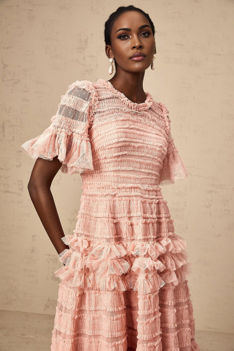 A pink midi dress with dot details and ruffled tulle accents featuring a feminine silhouette