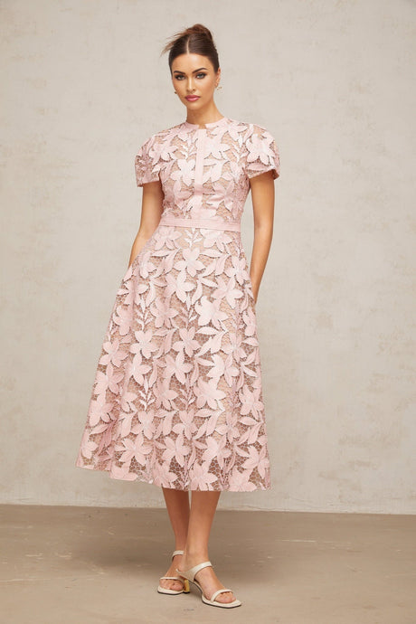 A pink midi dress with intricate guipure lace detailing feminine silhouette and delicate floral patterns throughout