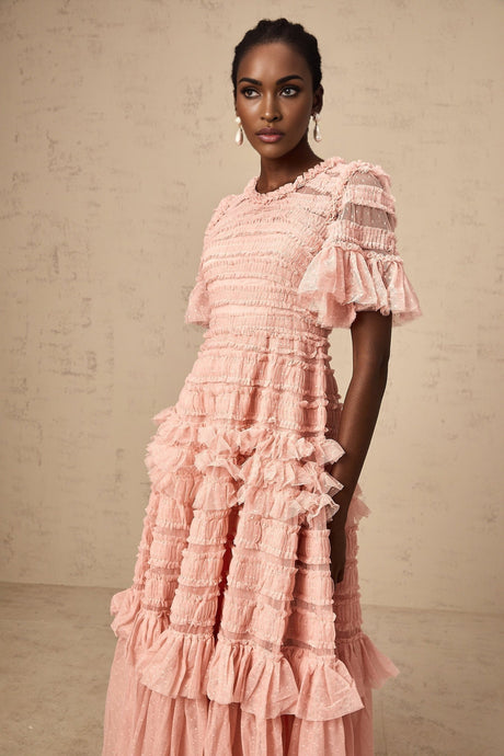 A pink midi dress with ruffled tulle fabric and small dot details throughout the design
