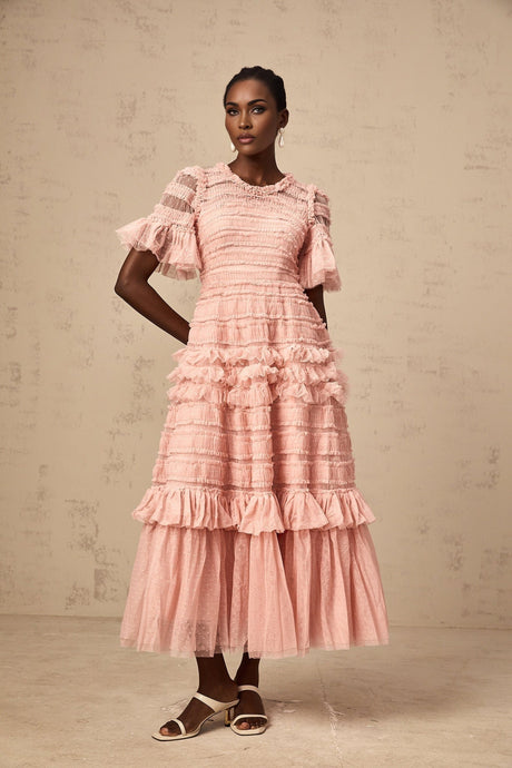 A pink midi dress with ruffled tulle featuring small dot details and a flowy silhouette