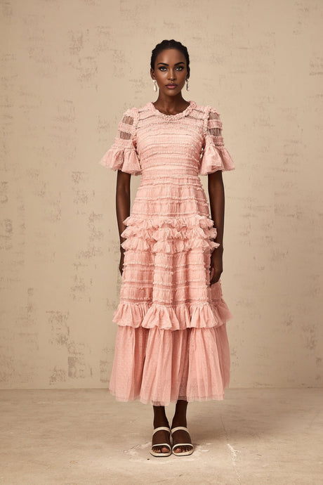 A pink midi dress with ruffles and tulle fabric featuring small dot details throughout the design