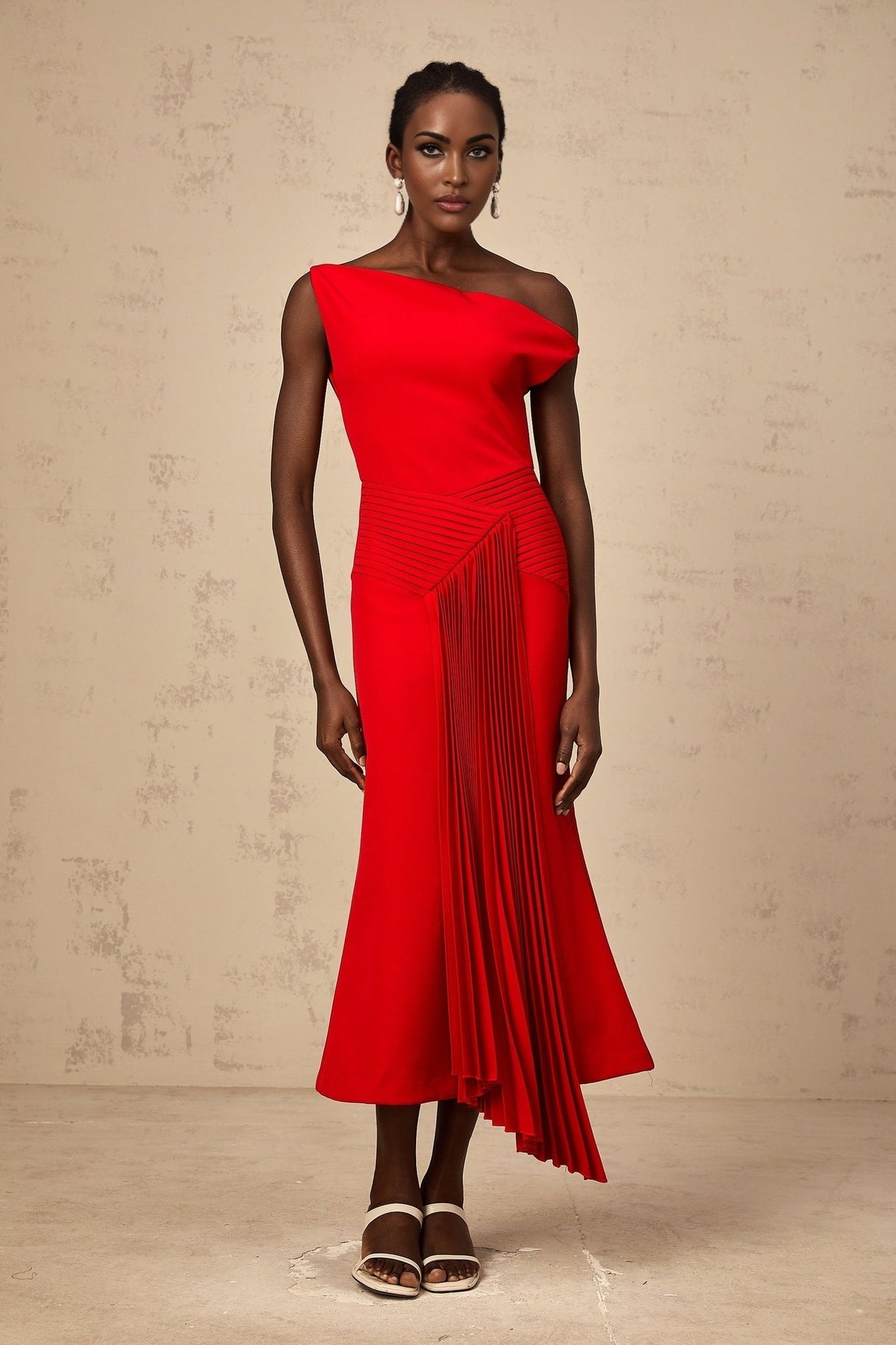 A red asymmetric midi dress with draped fabric details and an uneven hemline worn by a model against a plain background