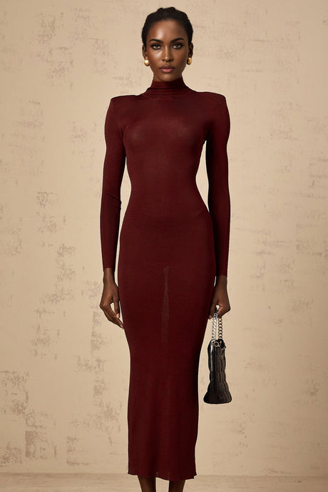 A red knitted midi dress with a semi sheer texture worn by a model standing against a plain background