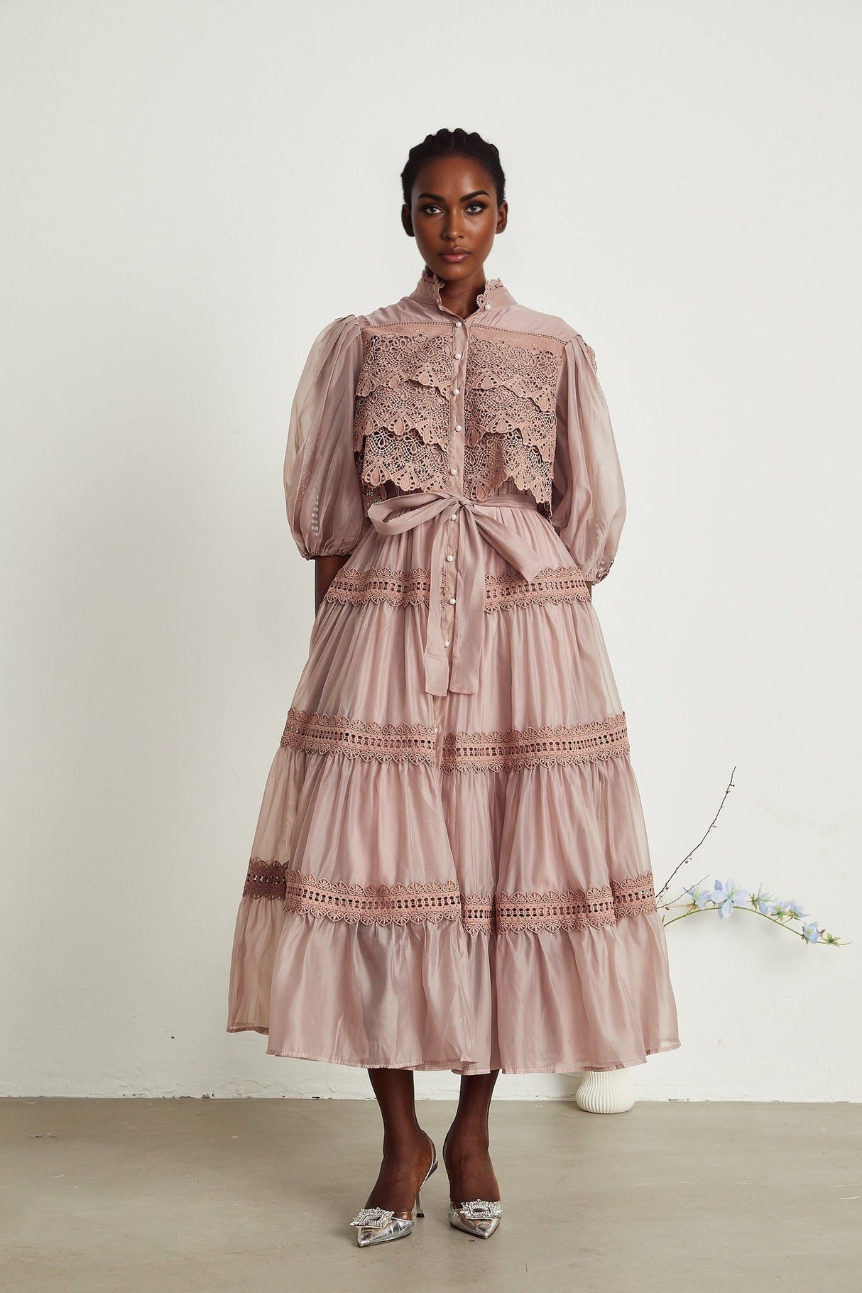 A tiered midi dress with lace detailing and cut out sections featuring a feminine silhouette in a delicate design