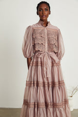 A tiered midi dress with lace detailing and cut out sections featuring a feminine silhouette in a soft color palette